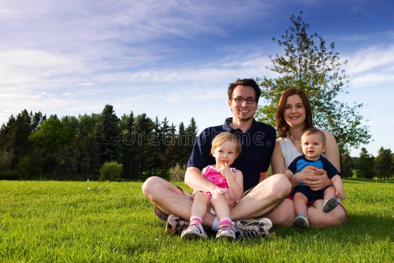 Una giovane famiglia in posa durante una giornata al parco in estate.