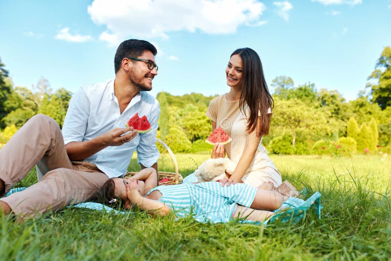 Family In Park. Happy Young Parents And Child Relaxing Outdoors