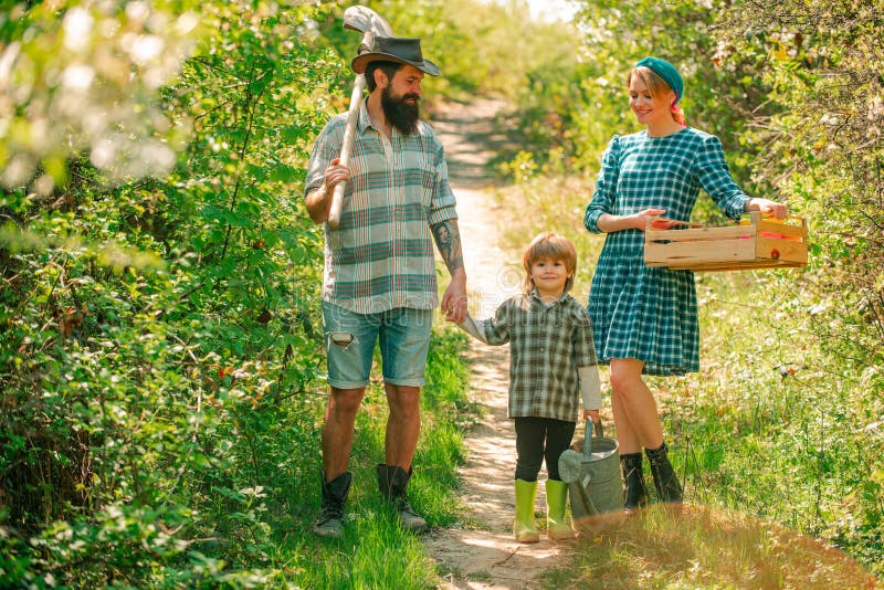 Family planting. Cheerful family of farmers standing in vegetable garden.