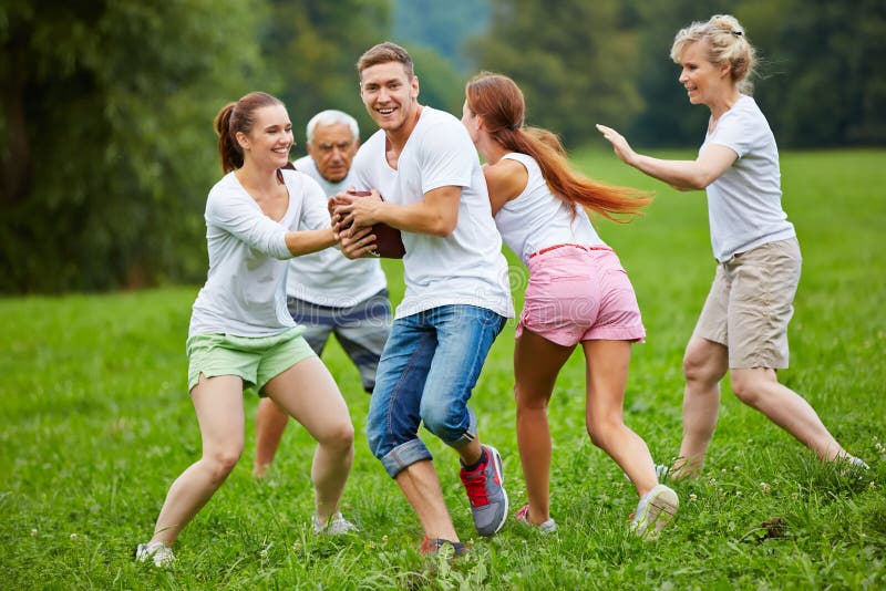 Family playing american football in garden. Smiling family playing american football on a meadow in their garden royalty free stock image