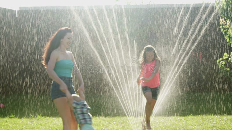 Family Playing on the Lawn Water Sprinkling on Mother with Children