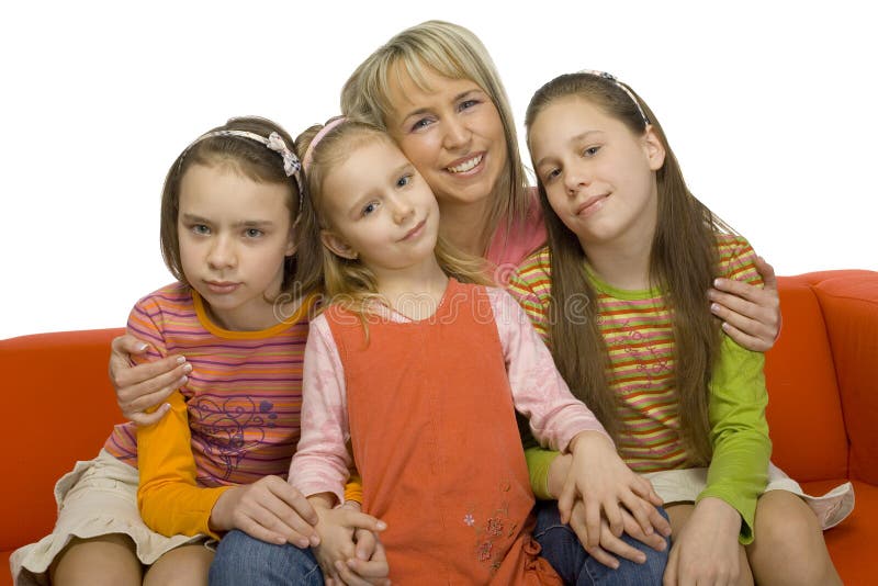 Family portrait. There're 3 girls and their mother sitting on the orange couch. They're looking at camera.