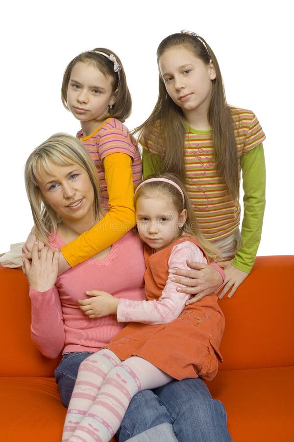 Family portrait. There're 3 girls and their mother. Some of them are sitting on the orange couch. They're all looking at camera.