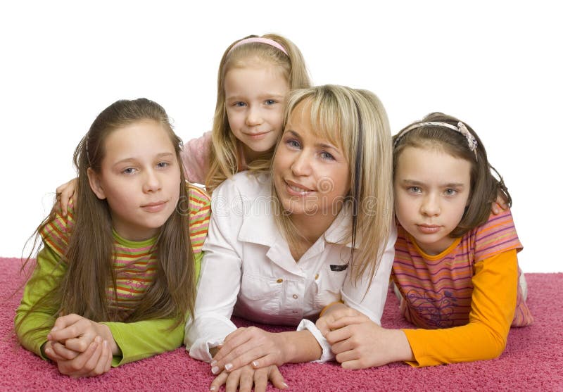 Family portrait. There're 3 girls and their mother lying on the pink carpet. They're looking at camera. Family portrait. There're 3 girls and their mother lying on the pink carpet. They're looking at camera.