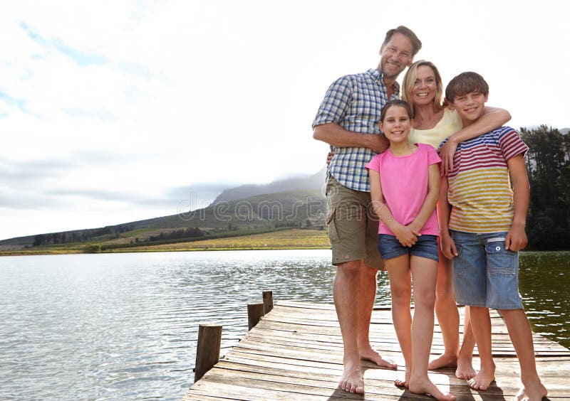 Family, portrait by lake and outdoor on pier for travel with vacation, parents and kids with fresh air in nature for