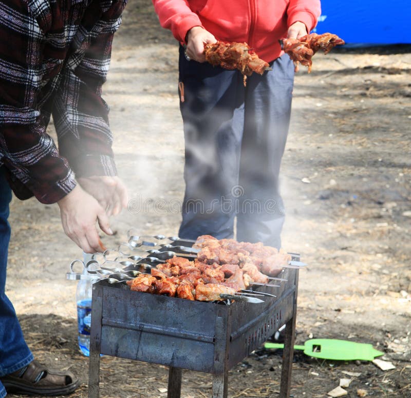 Familia preparación de sobre el parrilla sobre el Descansar afuera.