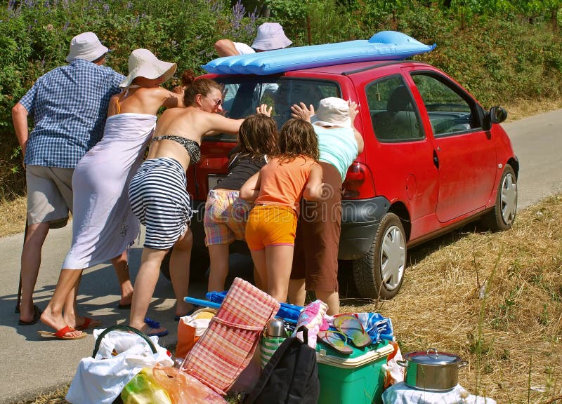 Large families (three generation family - grandma and grandpa with his children- son, daughters, grandchildren) with luggage went on summer vacation. The car (renault - twingo) is broken and they must push it. They were tired and sweaty. Horizontal color photo. Large families (three generation family - grandma and grandpa with his children- son, daughters, grandchildren) with luggage went on summer vacation. The car (renault - twingo) is broken and they must push it. They were tired and sweaty. Horizontal color photo.