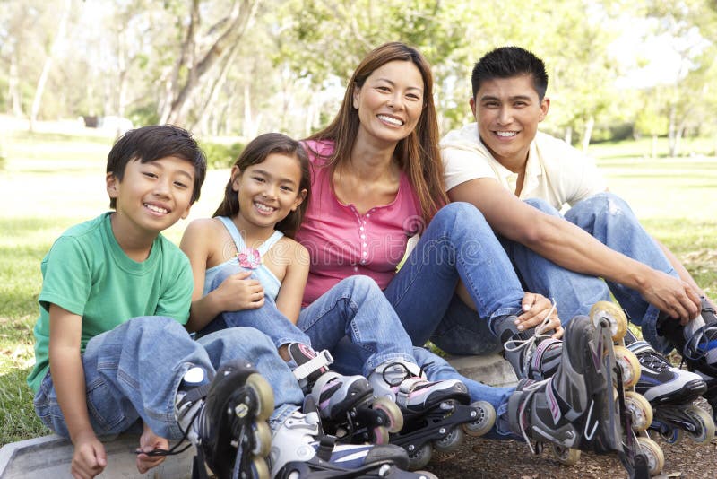 Asian Family Putting On In Line Skates In Park