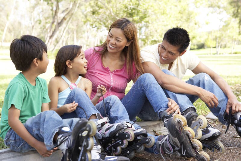 Asian Family Putting On In Line Skates In Park