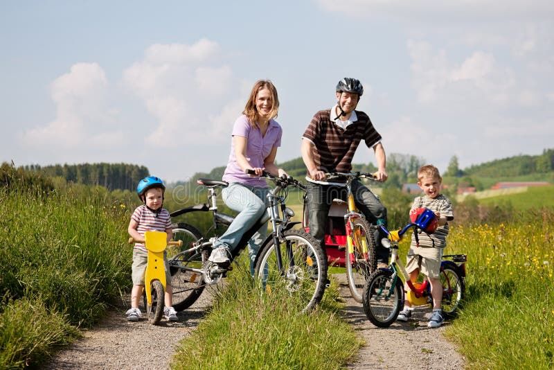 Famiglia con due bambini che hanno un escursione in bici in un giorno d'estate in un bellissimo paesaggio, per la sicurezza e la protezione che indossano caschi.