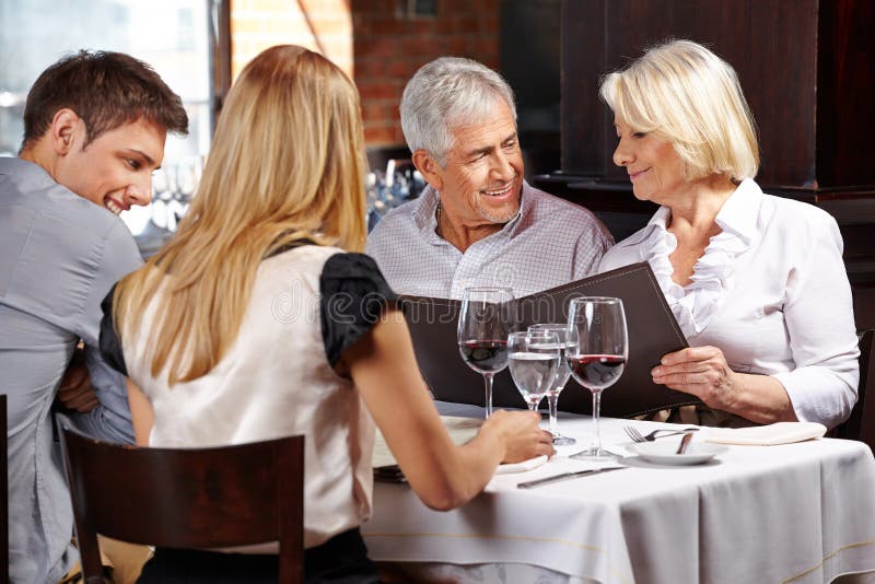 Family with two senior people in restaurant holding the menu. Family with two senior people in restaurant holding the menu