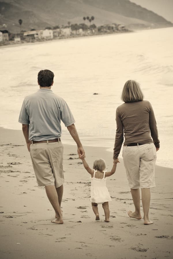 Eine Mutter und einen Vater zu Fuß am Strand entlang, mit Ihrem kleinen Kind.