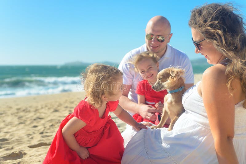 Family with sisters in red dress and dog on the beach