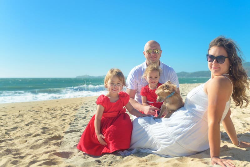 Family with sisters in red dress and dog on the beach