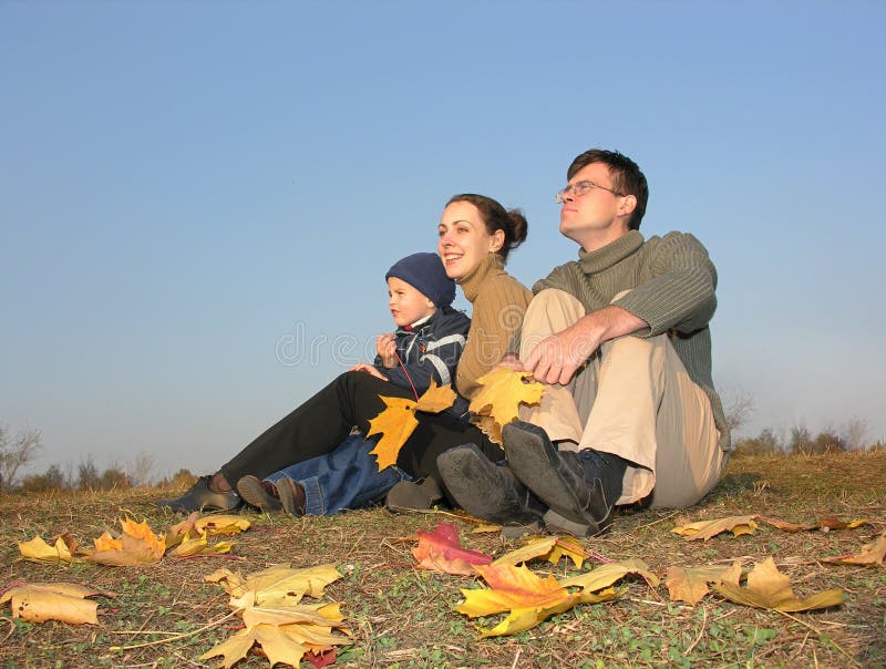 Familia sentarse otono hojas atardecer.