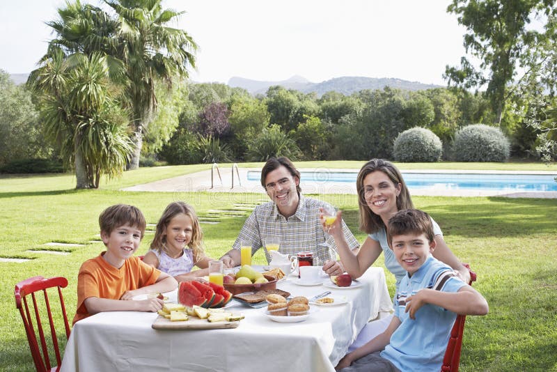 Family Sitting At Breakfast Table In Garden