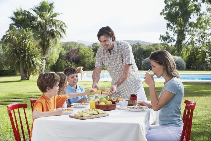 Family Sitting At Outdoor Breakfast Table