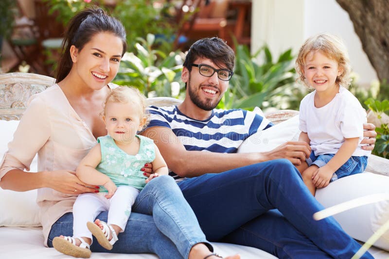 Family Sitting Outdoors In Garden At Home Together.