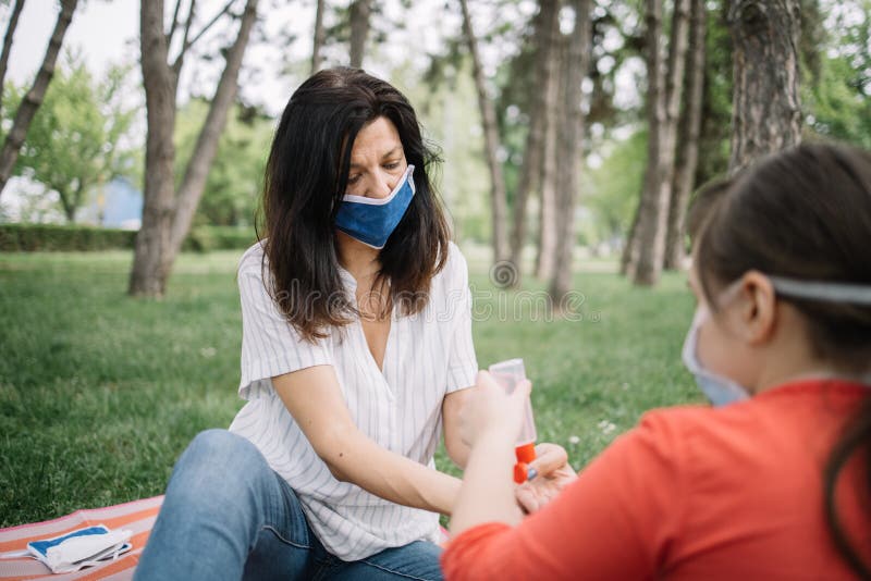 Family sitting in park and protecting themselves from virus while using hand sanitizer royalty free stock photo Family sitting in park and protecting themselves from virus while using hand sanitizer royalty free stock photo