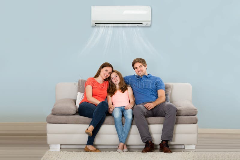 Family Sitting On Sofa Under Air Conditioning