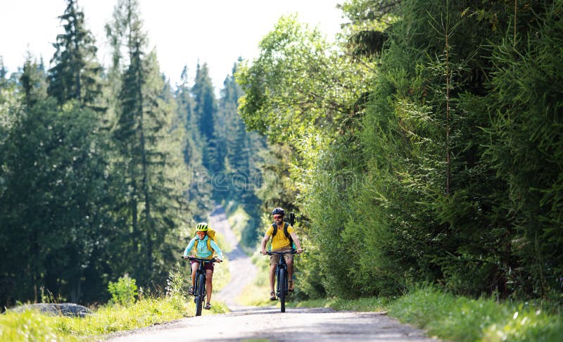 Rodina s malými deťmi na bicykli vonku v letnej prírode.