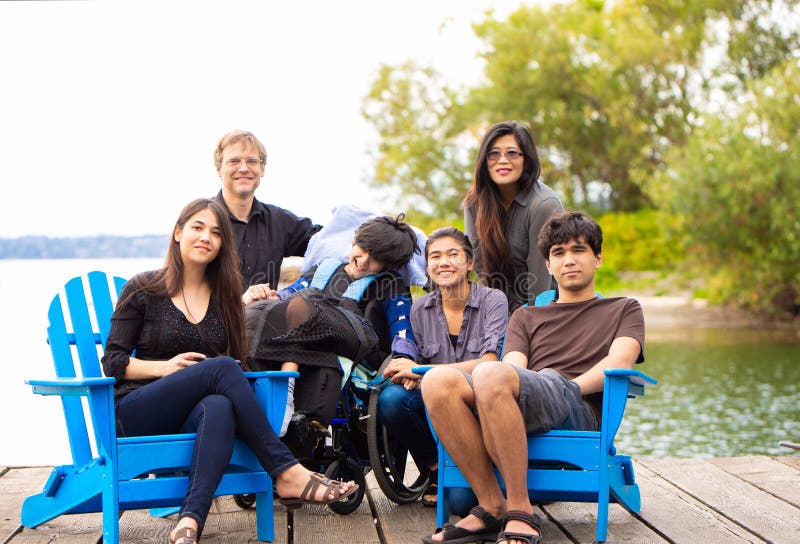 Family with special needs child sitting outdoors together in sum royalty free stock image Family with special needs child sitting outdoors together in sum royalty free stock image