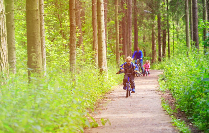 Family sport - father and kids riding bikes in summer forest