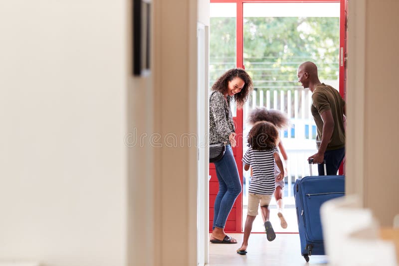 Family Standing By Front Door With Suitcase About To Leave For Vacation