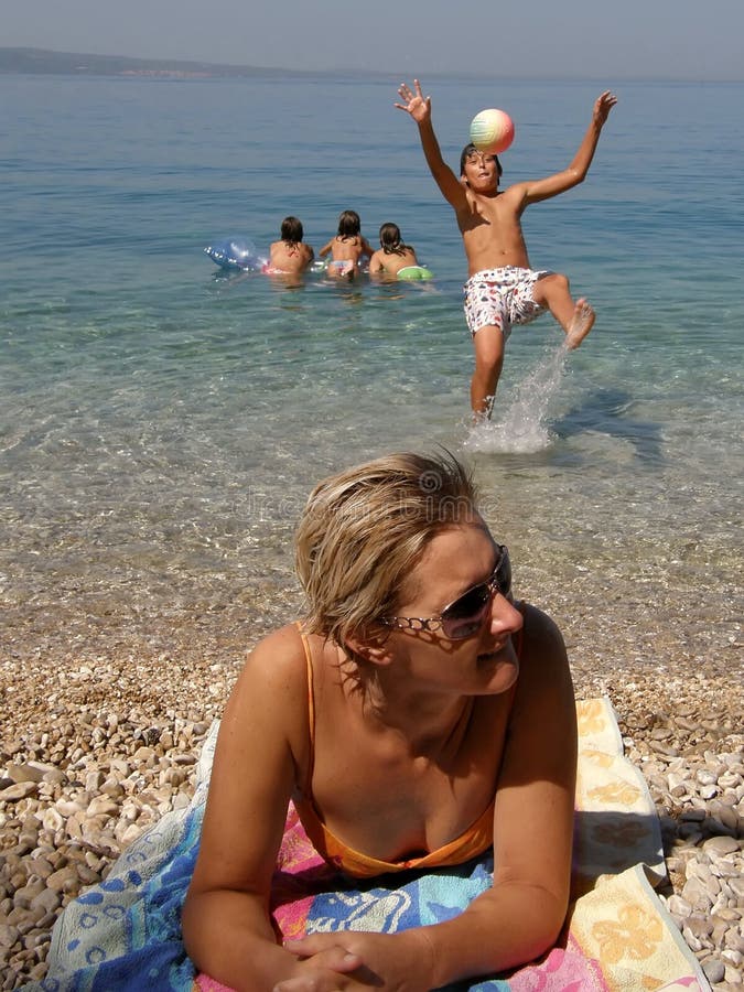 Madre (acostada sobre el guijarros Playa) a cuatro (el mejor amigos) sobre el verano día festivo.