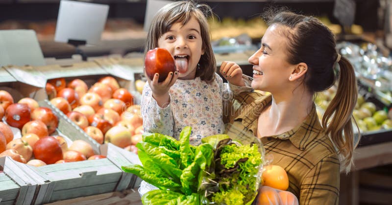 Family in the supermarket. Beautiful young mom and her little daughter smiling and buying food