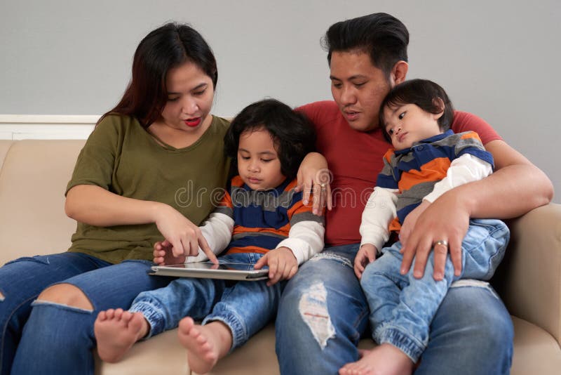 Filipino family gathered together to use an app on digital tablet. Filipino family gathered together to use an app on digital tablet