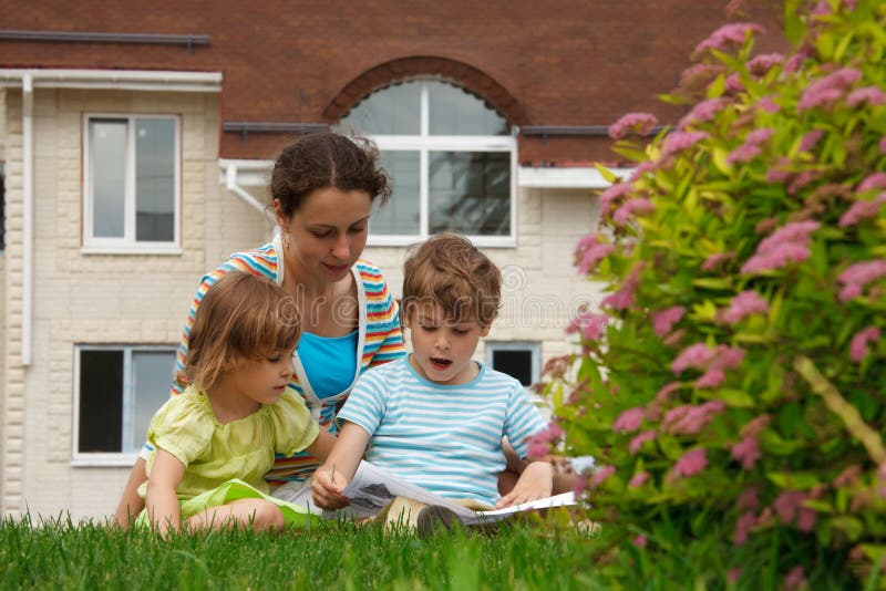 Family of three people on lawn in front of house stock images