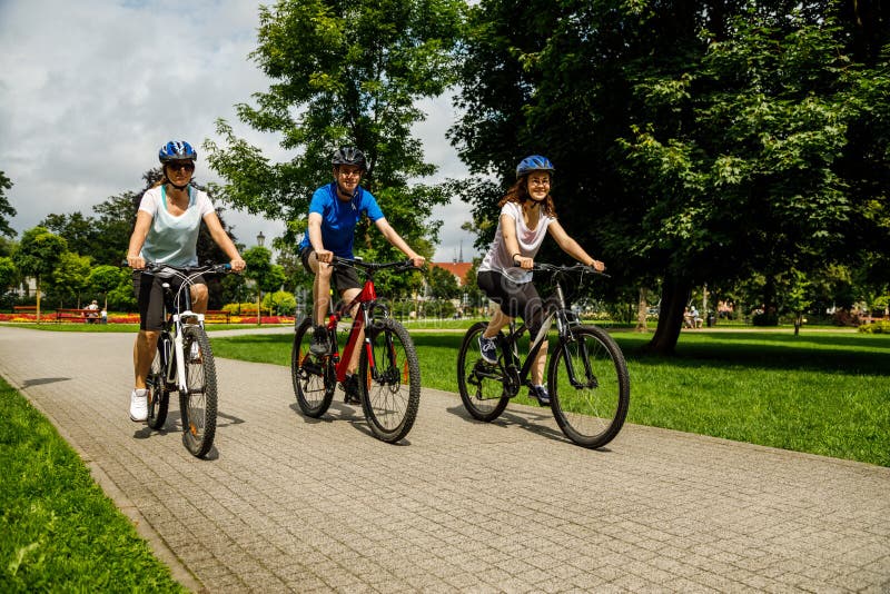 Family of three people riding bikes in summer park royalty free stock image