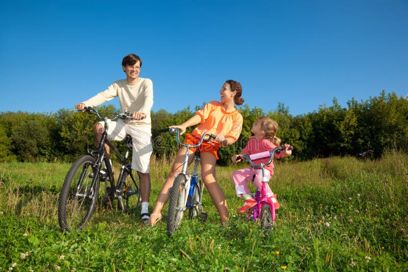 Family from three persons on bicycles in country.