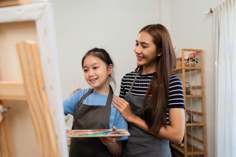 Family time focusing on creativity: Mother assisting daughter painting royalty free stock image
