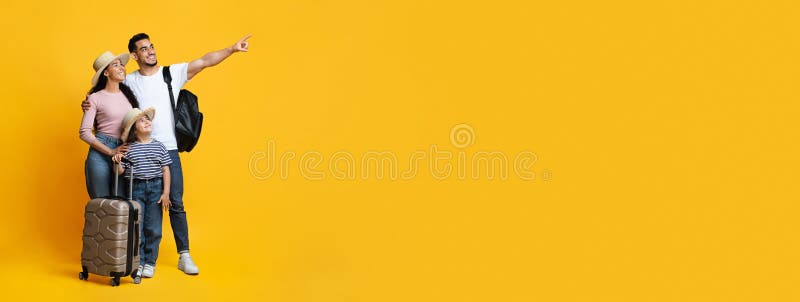 Family Travel Concept. Happy middle eastern parents with little daughter carrying suitcases. And pointing aside at copy space on yellow background, mom, dad and