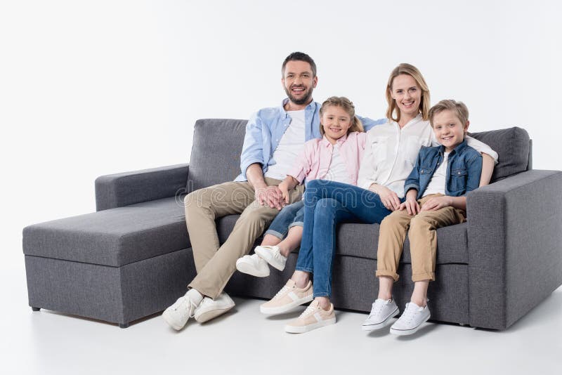 Family with two children sitting together on couch and smiling at camera stock photography Family with two children sitting together on couch and smiling at camera stock photography