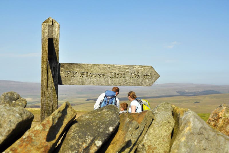 Family under signpost on top of hill