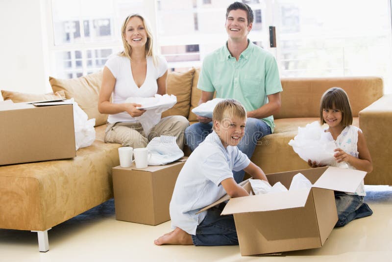 Famiglia disimballaggio caselle nella nuova casa di sorridere alla telecamera.