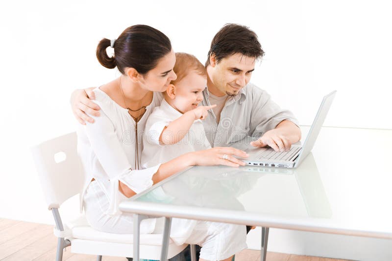 Family using laptop. Family with 2 years old baby boy sitting at the desk and using laptop computer Family using laptop. Family with 2 years old baby boy sitting at the desk and using laptop computer
