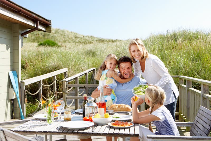 Familia sobre el día festivo comer afuera sobre el cubierta de Playa cabana.