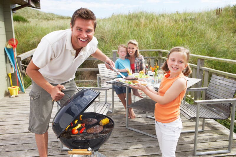 La famiglia in vacanza avendo il barbecue sulla spiaggia.
