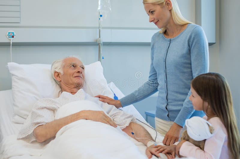 Family visiting ill grandfather. Mother and daughter in hospital to meet ill grandfather. Family in hospital go to visit happy senior man. Grandfather in stock image Family visiting ill grandfather. Mother and daughter in hospital to meet ill grandfather. Family in hospital go to visit happy senior man. Grandfather in stock image