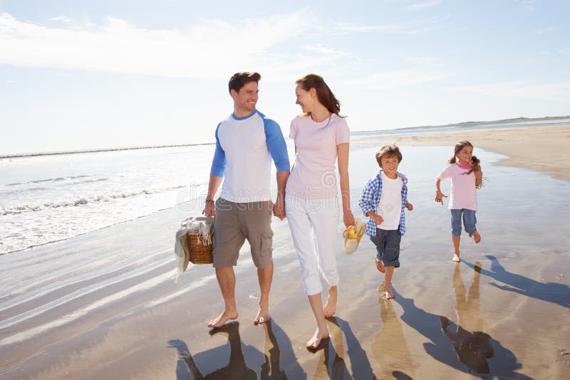 Family Walking Along Beach With Picnic Basket