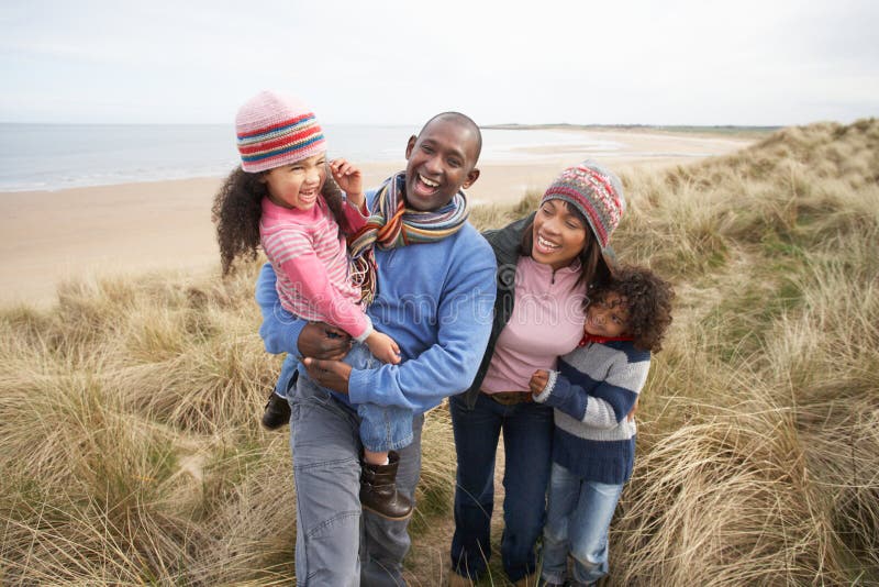 Family Walking Along Dunes On Winter Beach