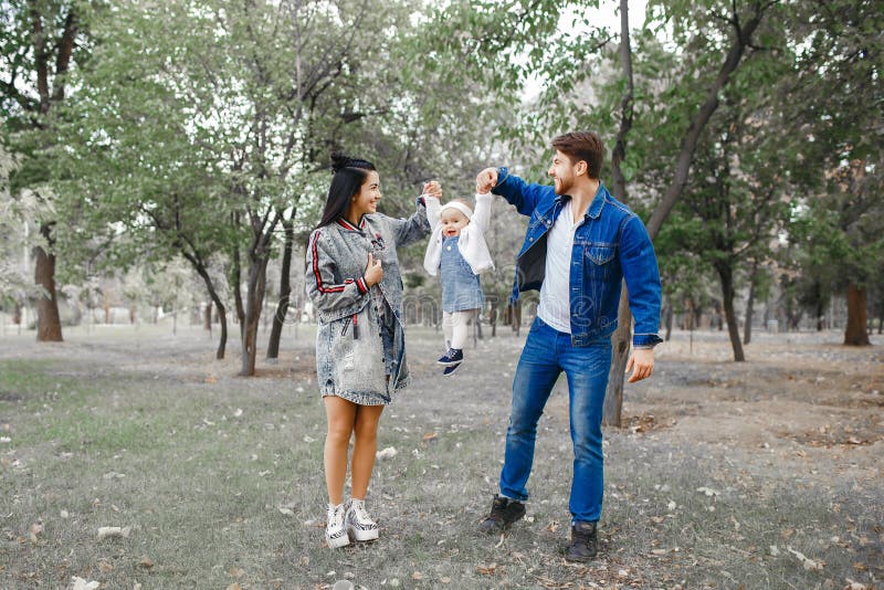 The family walks in the park, the mother keeps the little daughter above her head, the father takes care of the family stock photography The family walks in the park, the mother keeps the little daughter above her head, the father takes care of the family stock photography
