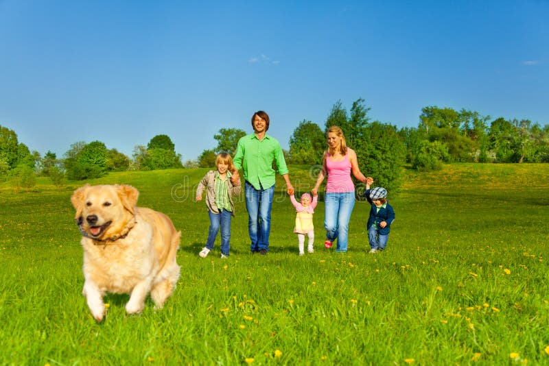 Happy family walks with running dog in park in summer