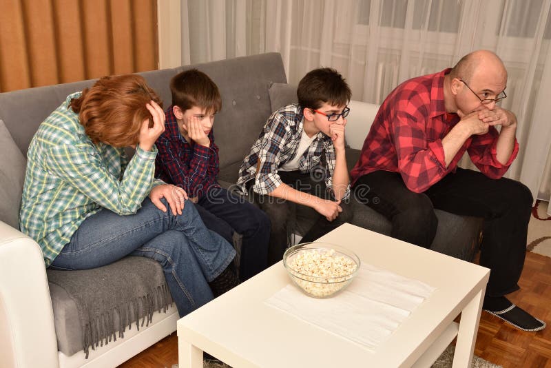 Family watching boring movie or program on TV. Bored family sitting on the sofa in the living room and watching a boring movie or program on TV royalty free stock images Family watching boring movie or program on TV. Bored family sitting on the sofa in the living room and watching a boring movie or program on TV royalty free stock images