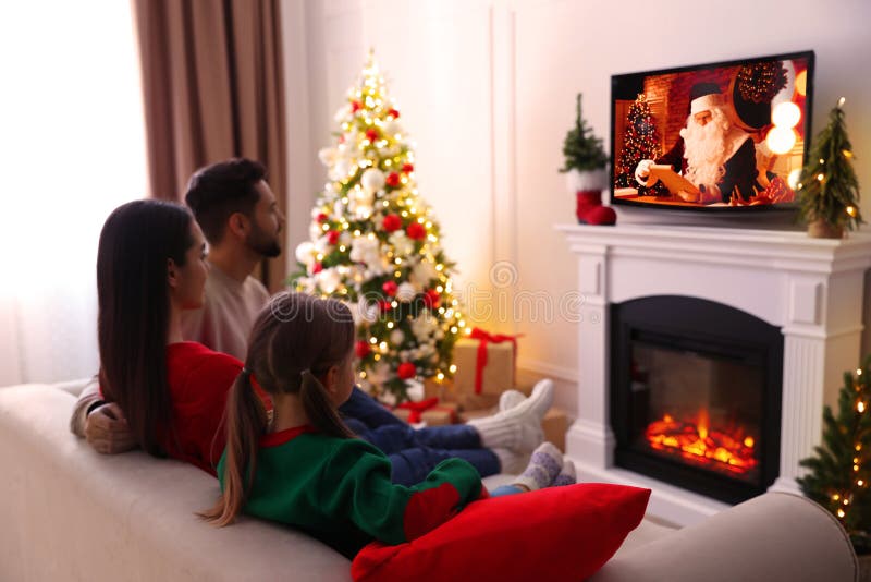 Family watching festive movie on TV in room decorated for Christmas