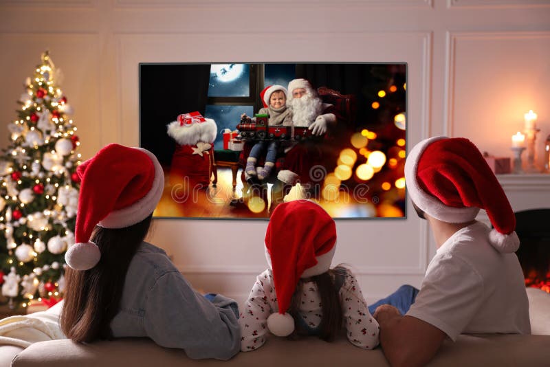 Family watching TV movie in room decorated for Christmas, back view